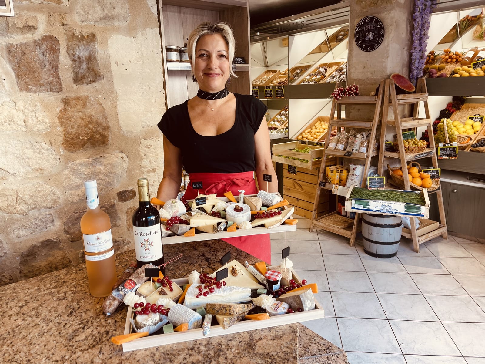 La fromagère présente deux plateaux de fromages composés en boutique